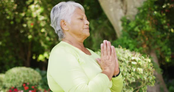 Video of relaxed biracial senior couple practicing yoga in garden