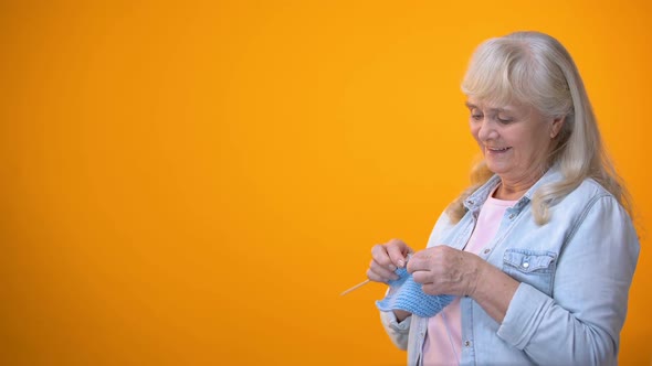 Cheerful Aging Woman Knitting and Smiling to Camera