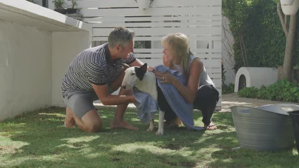 Couple washing dog in their garden