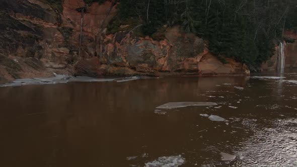 Low Angle Melting Snow and Ice at River Gauja Near Beautiful Sand Cliff Cinematic Aerial