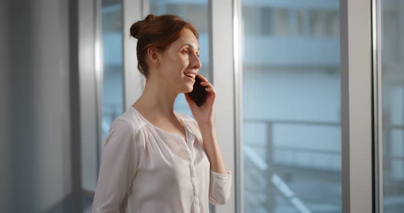 Businesswoman Talking on Phone in Modern Office with Panoramic Windows