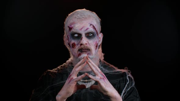 Frightening Man with Halloween Zombie Bloody Wounded Makeup Trying to Scare Praying Horror Theme