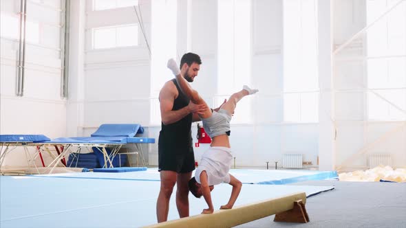 A Young Athlete is Making a Handstand on Beam and Push Up Headfirst Side View