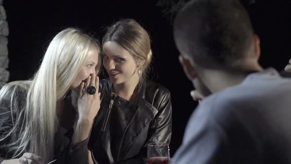 Young Woman Tell a Secret to Her Friend and Smile While Enjoying Aperitif in Outdoor Rural Scenic at