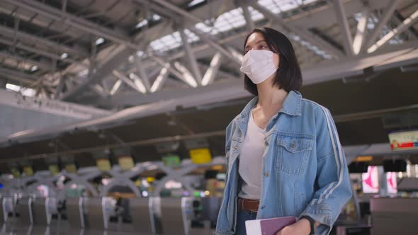 Woman passenger wearing face mask walking in airport terminal to boarding gate during the COVID.