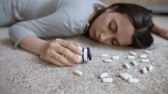 Unconscious Woman with Pills in Her Hands Lies on the Floor