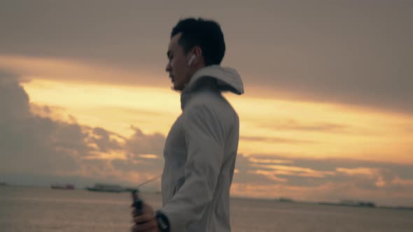 A handsome Asian sportsman in sports clothing skipping rope while exercising workout.