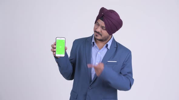 Happy Bearded Indian Sikh Businessman Showing Phone and Giving Thumbs Up