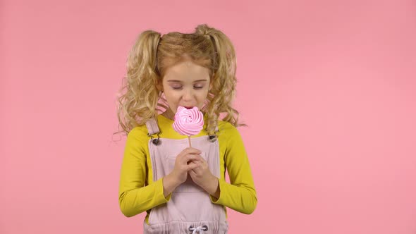 Pretty Female Child Is Eating a Candy on the Stick