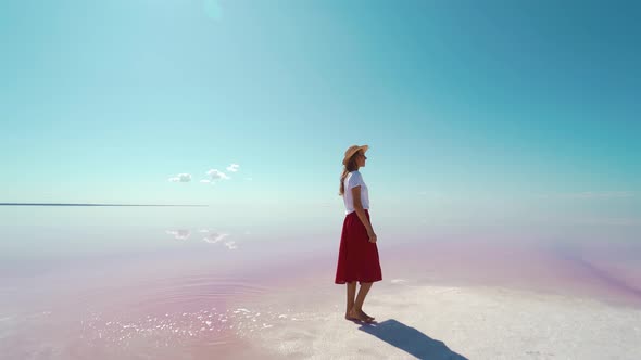 Tourist Woman in Red Skirt and Hat Walking By Salt Flats Beach at Pink Lake