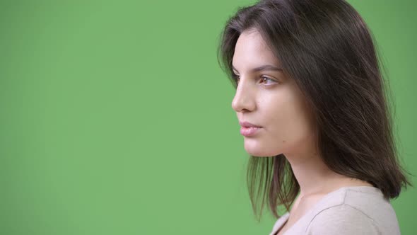 Profile View of Young Beautiful Woman Against Green Background