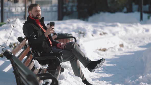 Man Enjoying Hot Coffee on Snowy Bench