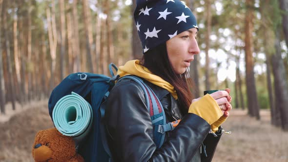 Woman Hiker Having Rest with Hot Drink Tea From Thermos on the Pine Forest