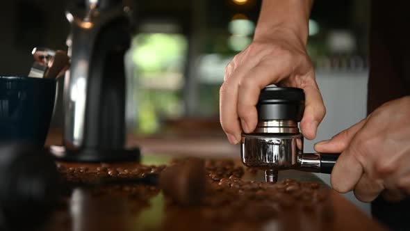 The barista is preparing the ground coffee to make espresso for the customers in the morning.