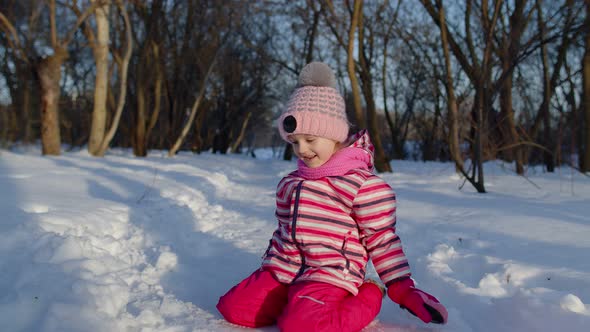 Joyful Little Child Girl Running Towards on Snowy Road Looking at Camera in Winter Park Forest