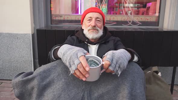 Homeless Man in Old Clothes Sitting on Cardboard Box Asking for Money, for Any Help.