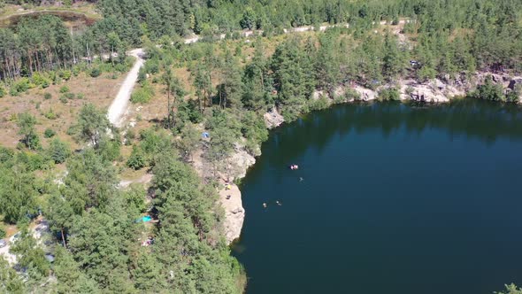 Aerial drone video of a large lake surrounded by a pine tree forest in Kyiv Oblast Ukraine on a hot