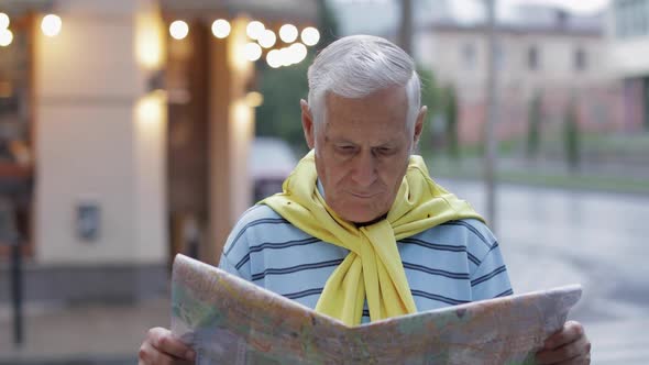 Senior Male Tourist Exploring Town with a Map in Hands and Looking for the Route