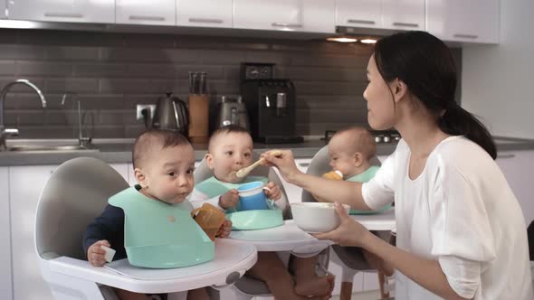 Asian Mom Posing in Kitchen with Triplets during Feeding