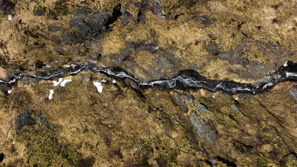 Drone tracking river flowing down rugged rocky Italian alp mountain hillside