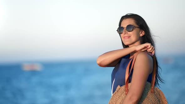 Portrait of Fashion Brunette Girl with Bag Posing at Sea Background Enjoying Freedom