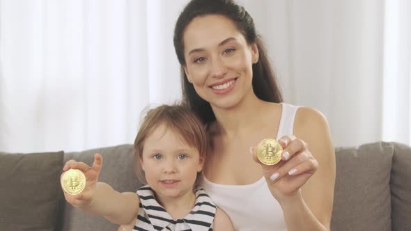 A Young Mother and Her Daughter Show Bitcoin in Their Hand