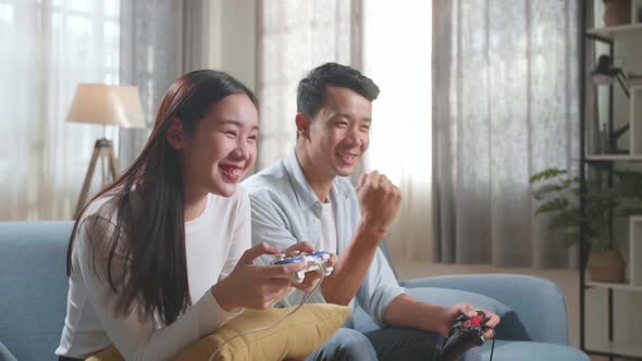 Young Asian Couple With Joystick Play Video Game On Tv And Celebrating Victory