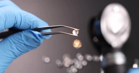 Jeweler in Gloves with Magnifying Glass Examines Precious Stones