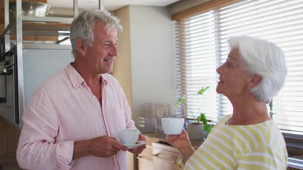 Senior caucasian couple having talking to each while having coffee together in the kitchen at home