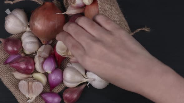 A Hand Picking Up Some Compound Bulb Of Garlics From Top View