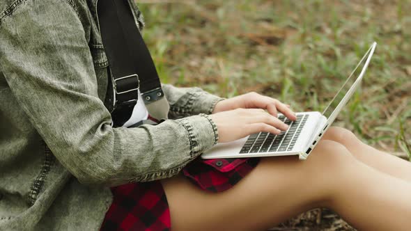 Beautiful Unrecognizable Woman Using Laptop in the Nature. Freelancer Working Surrounded By Trees