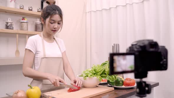 Blogger Asian woman using camera recording how to make salad healthy food video for her subscriber.