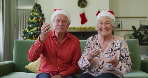 Happy caucasian senior couple in santa hats on video call at christmas time