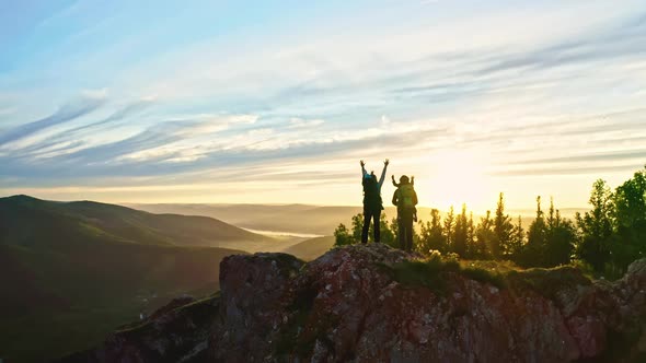 Drone Shot of a Family with Children Raising Their Hands Up Standing on the Top of a Mountain at