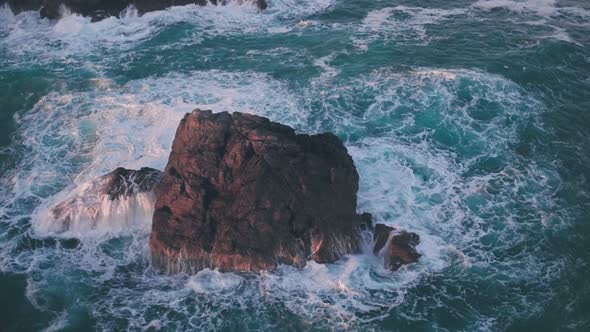 Waves crashing on rocks on Guernsey Coastline at sunset, Channel Islands, UK. Aerial drone view