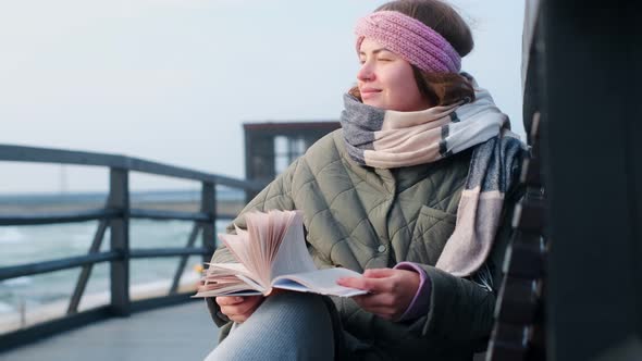 Woman in Warm Clothes Reads a Book at the Stormy Nothern Sea