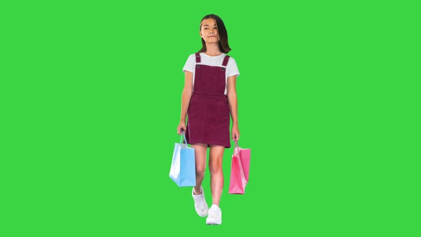 Little Girl in Casual Walking with Shopping Bags on a Green Screen Chroma Key