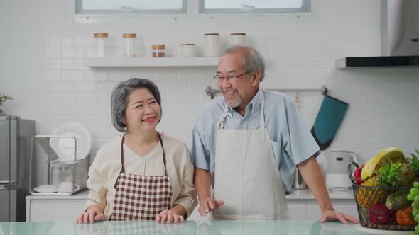 Portrait of Asian senior elderly couple stand with happiness in kitchen and smile, look at camera.
