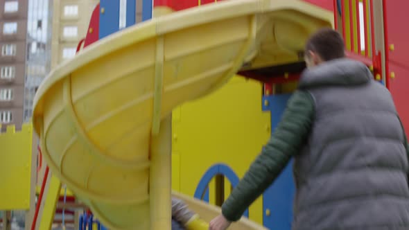 Young Caucasian Parents Having Fun with Son on Slide alt