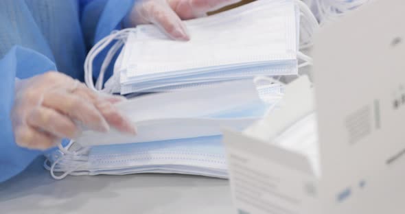 Factory Worker In Disposable Gloves Counting Surgical Masks On Table Before Boxing. close up