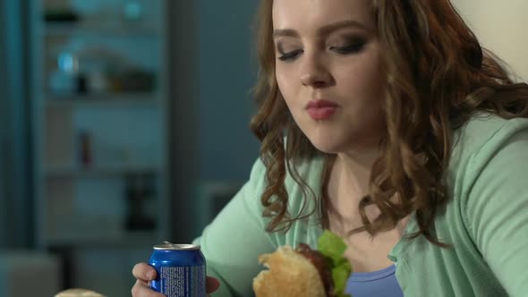 Young Woman Enjoying Her Burger and Looking at It With Admiration During Movie