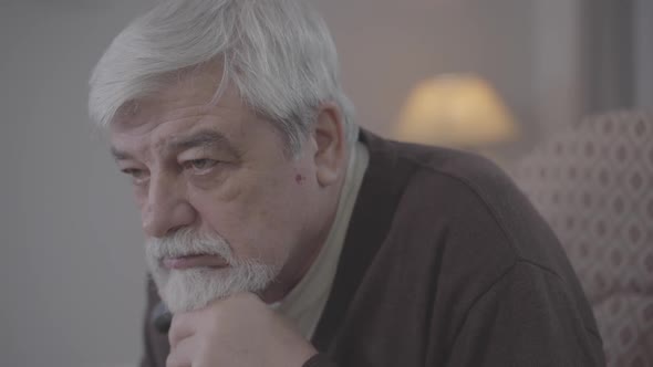 Side View Close-up of Desperate Caucasian Old Man Sighing. Portrait of Brown-eyed Grey-haired