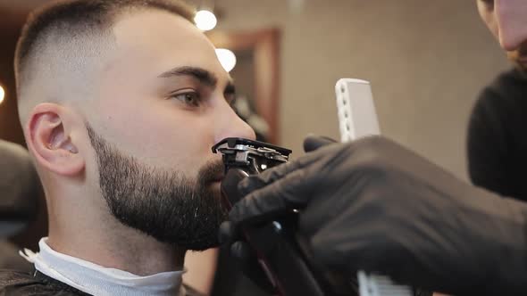 Hairstyling Process. Close-up of a Barber Drying Hair of a Young Bearded Man