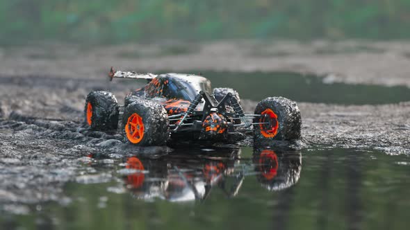 Dirty, orange RC-Car got stuck in the mud on a wet forest mire path. 4KHD