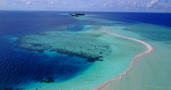 Wide flying clean view of a paradise sunny white sand beach and blue sea background in 4K