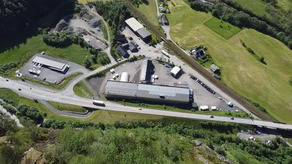 Flying over the edge of high cliff watching Norwegian highway E-16 and industrial area Dalegarden fa