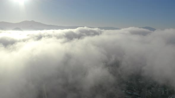 Aerial view of low fog over mountains in San Diego during sunrise