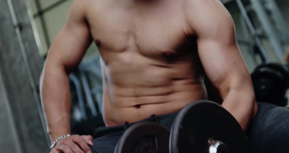 Young Asian Bodybuilder in training in the gym. Young man doing biceps exercise with dumbbells.