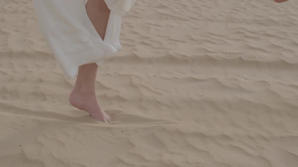 Young Girl in a Dress Dancing in the Sand