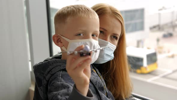 A Mother with a Son with Masks at the Airport Boy is Playing with a Airplane